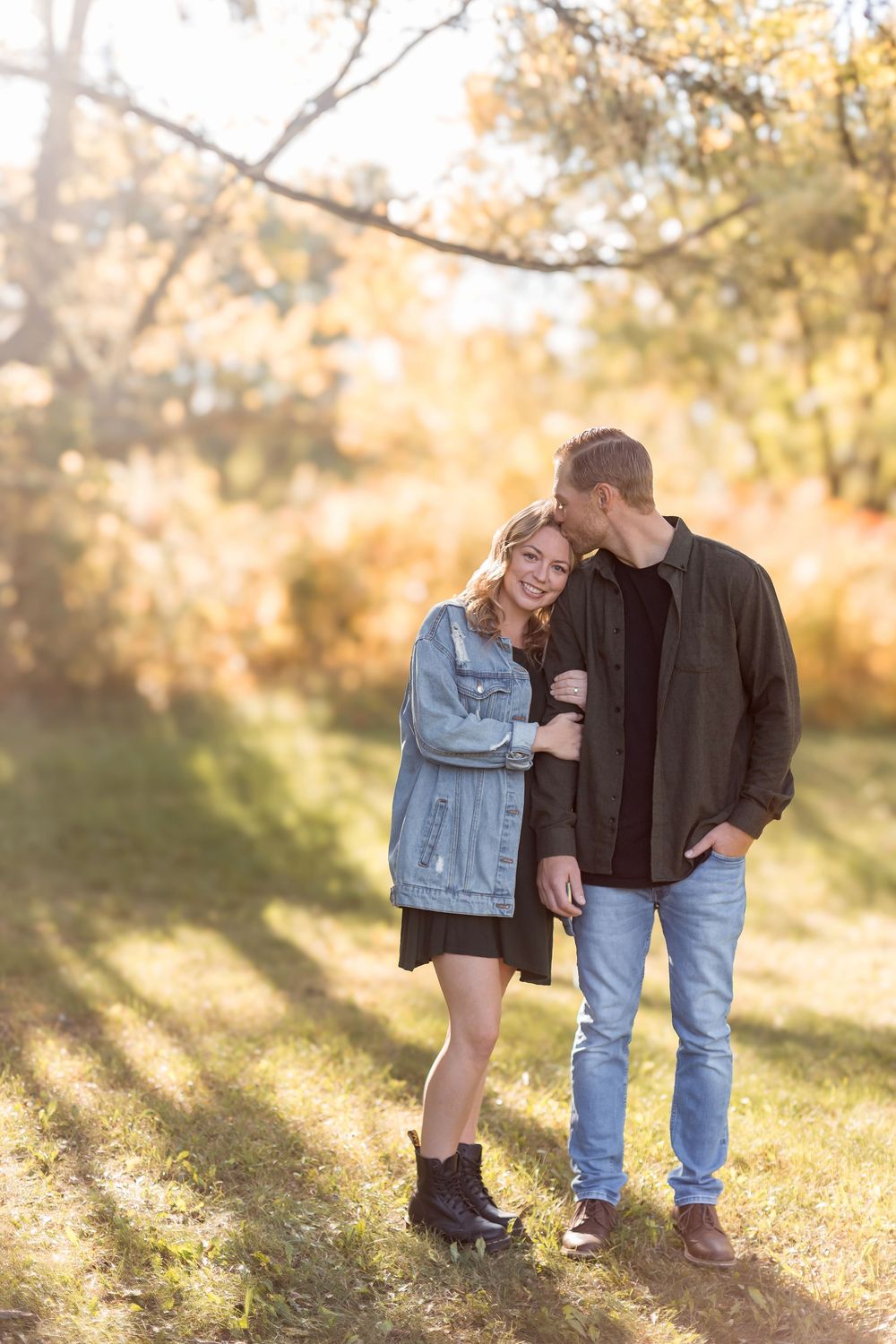 Couple embracing in autumn park with golden foliage in warm sunlight.