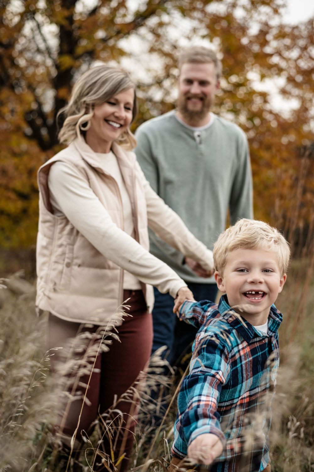 Family enjoying a playful moment together in tall autumn grass.