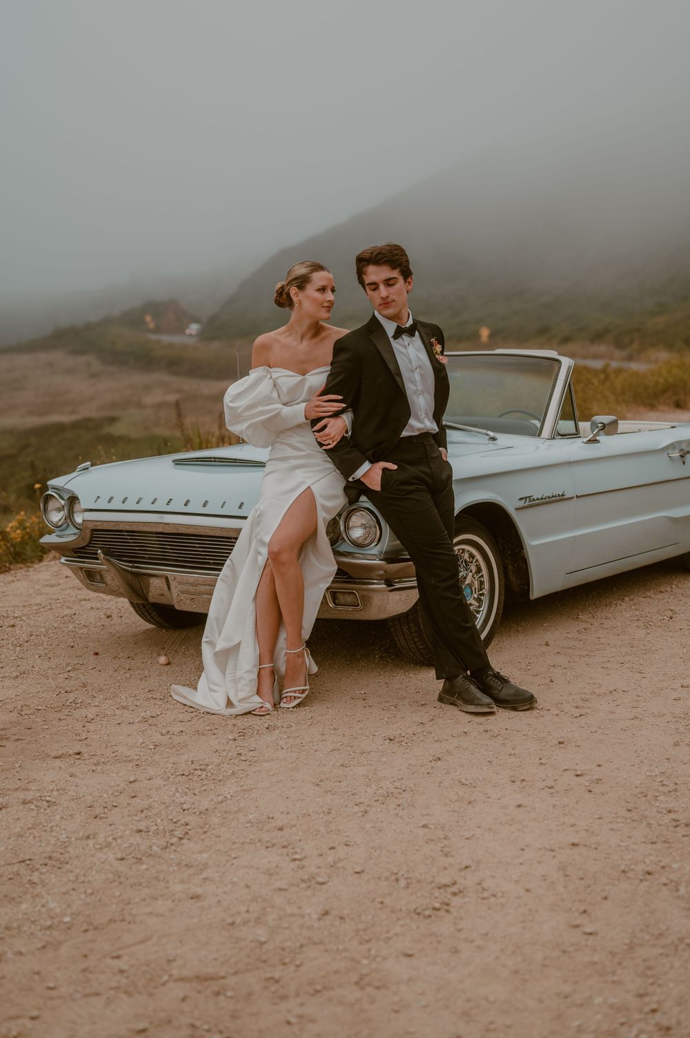 A vintage blue convertible with an elopement wedding couple posing in Big Sur. photo by Samantha Campbell imagery