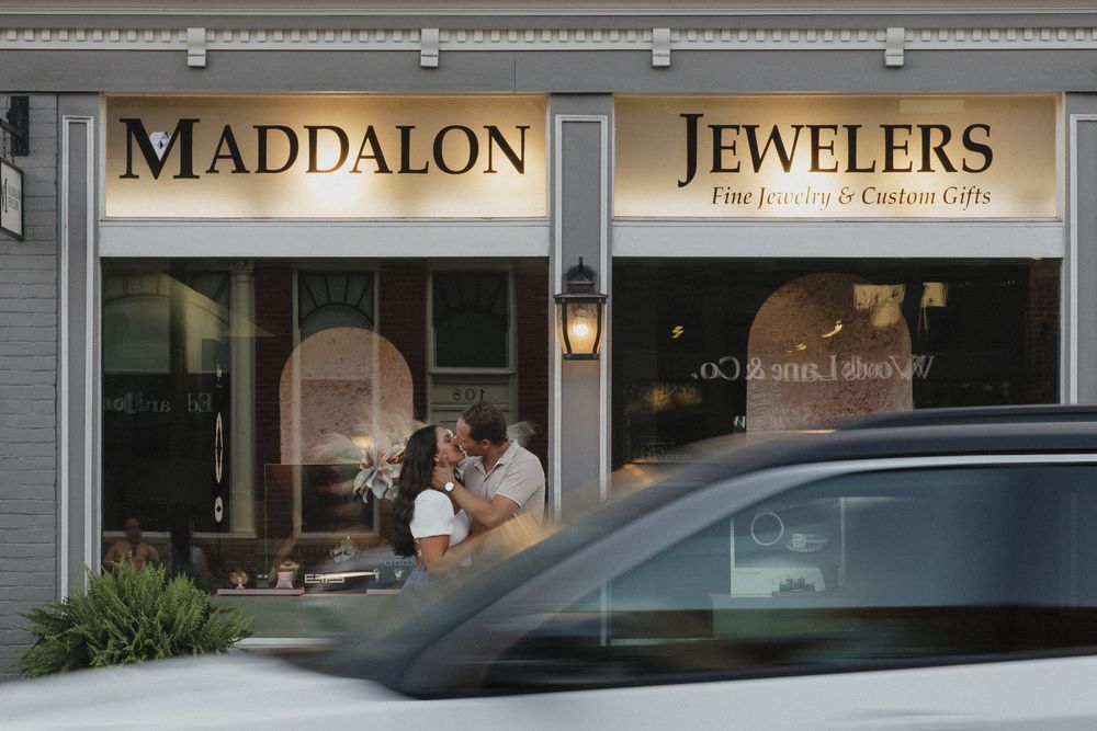 Exterior storefront view of Maddalon Jewelers with illuminated signage and display windows at dusk.