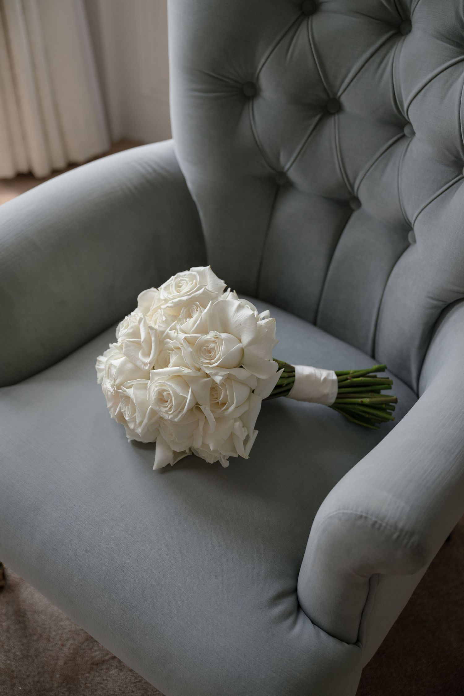 Wedding shoes and white floral bouquet arrangement on dark wooden table.