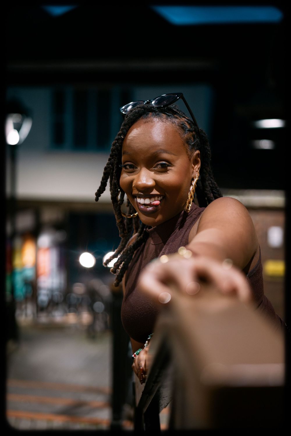 A series of candid nighttime portraits showing joyful expressions and braided hairstyles in an urban setting.
