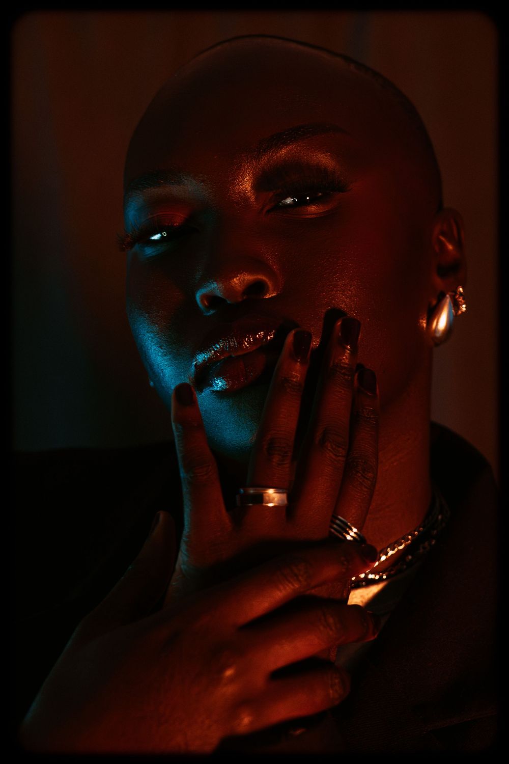 Artistic portrait series in dark lighting with dramatic red and blue tones showing close-up facial expressions.