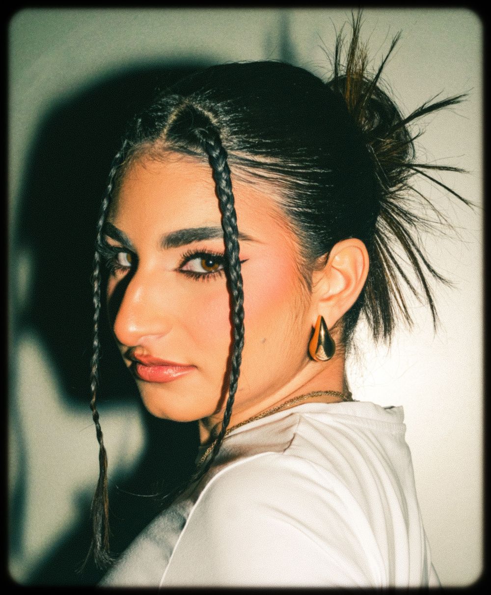 Artistic profile portraits showing braided dark hair and white clothing against a moody dark background.