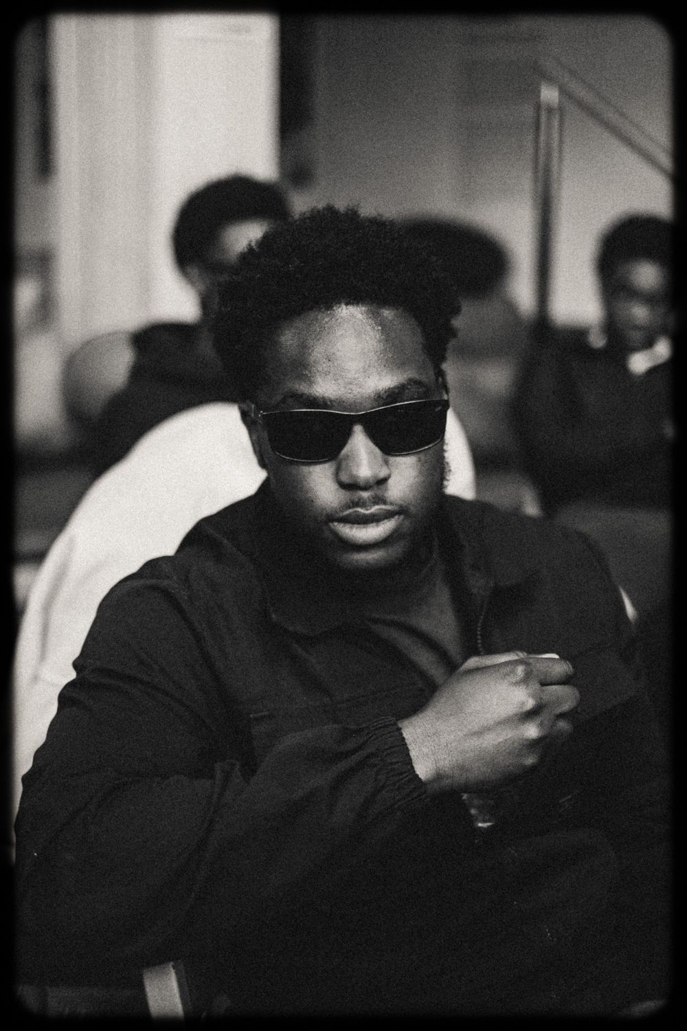 Black and white portrait series showing someone wearing sunglasses and dark clothing in moody lighting.