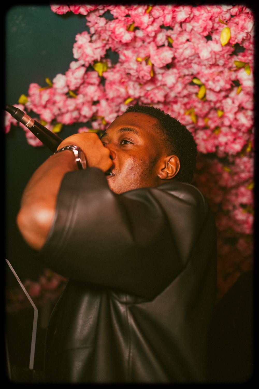 Artistic photo series of a performer in black jacket against pink cherry blossoms at night.