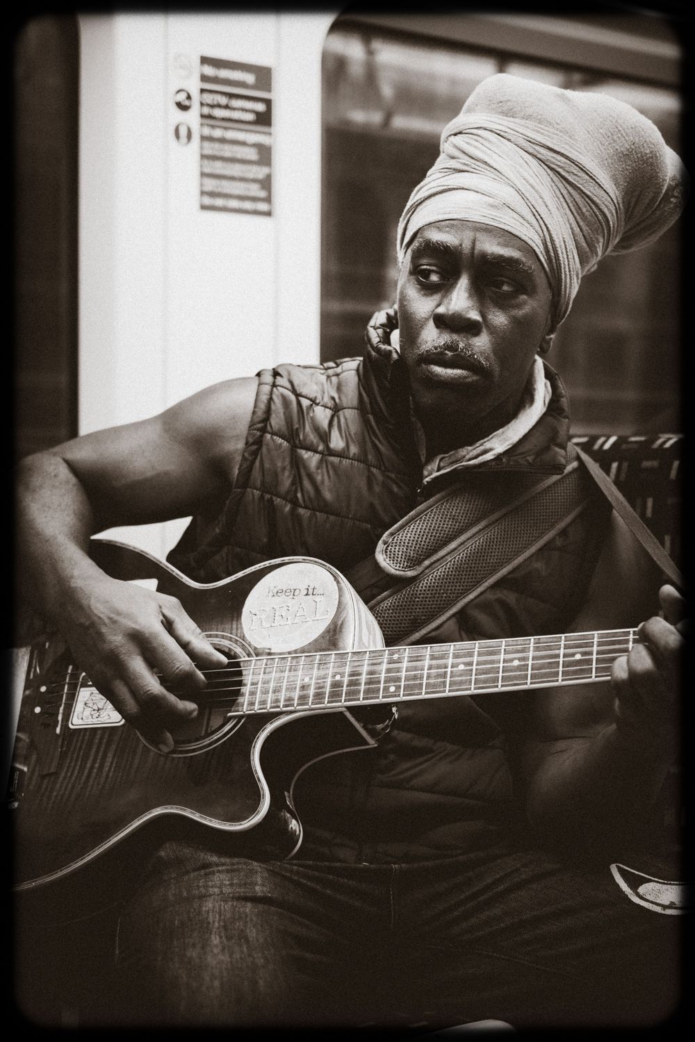 Black and white photo series of a musician playing acoustic guitar while wearing a head wrap, captured in moody lighting.