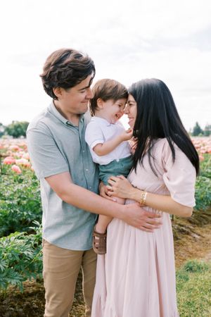 A tender family moment shared in a flower field on a bright summer day.
