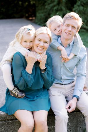 A cheerful outdoor family portrait with parents and small children cuddling together.