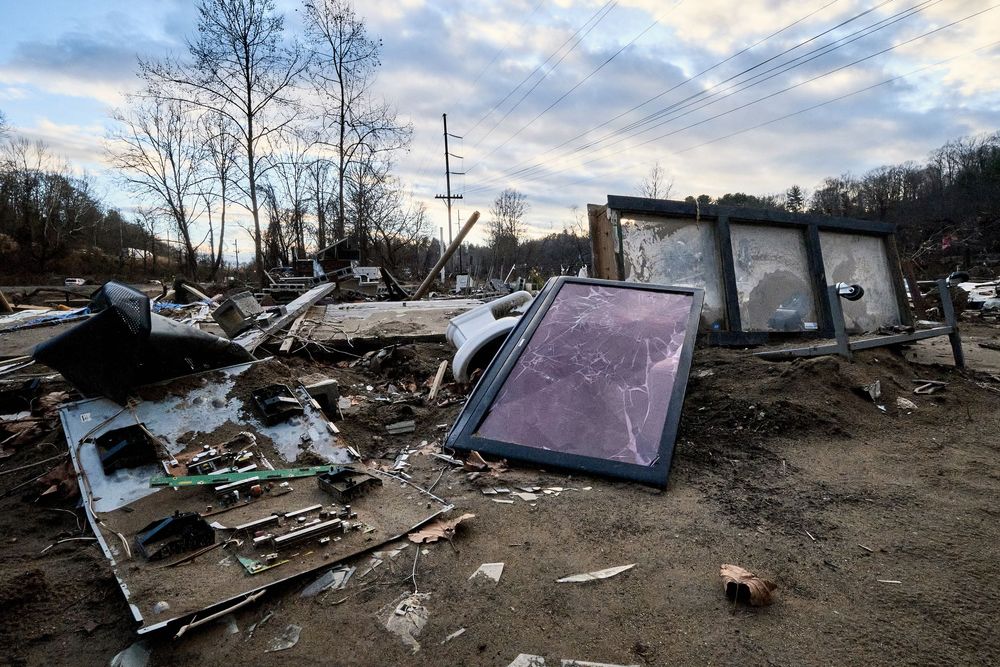 Debris and destruction scattered across a disaster site with broken frames and rubble under a cloudy sky.