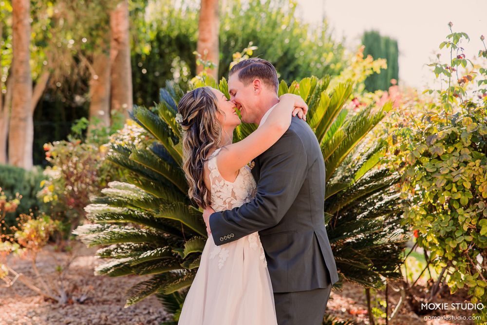 Elegant wedding photography in a garden setting with natural sunlight filtering through trees.