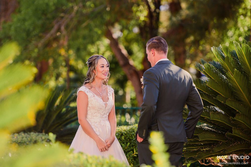 A couple shares a romantic moment in a lush garden setting during a wedding photoshoot.