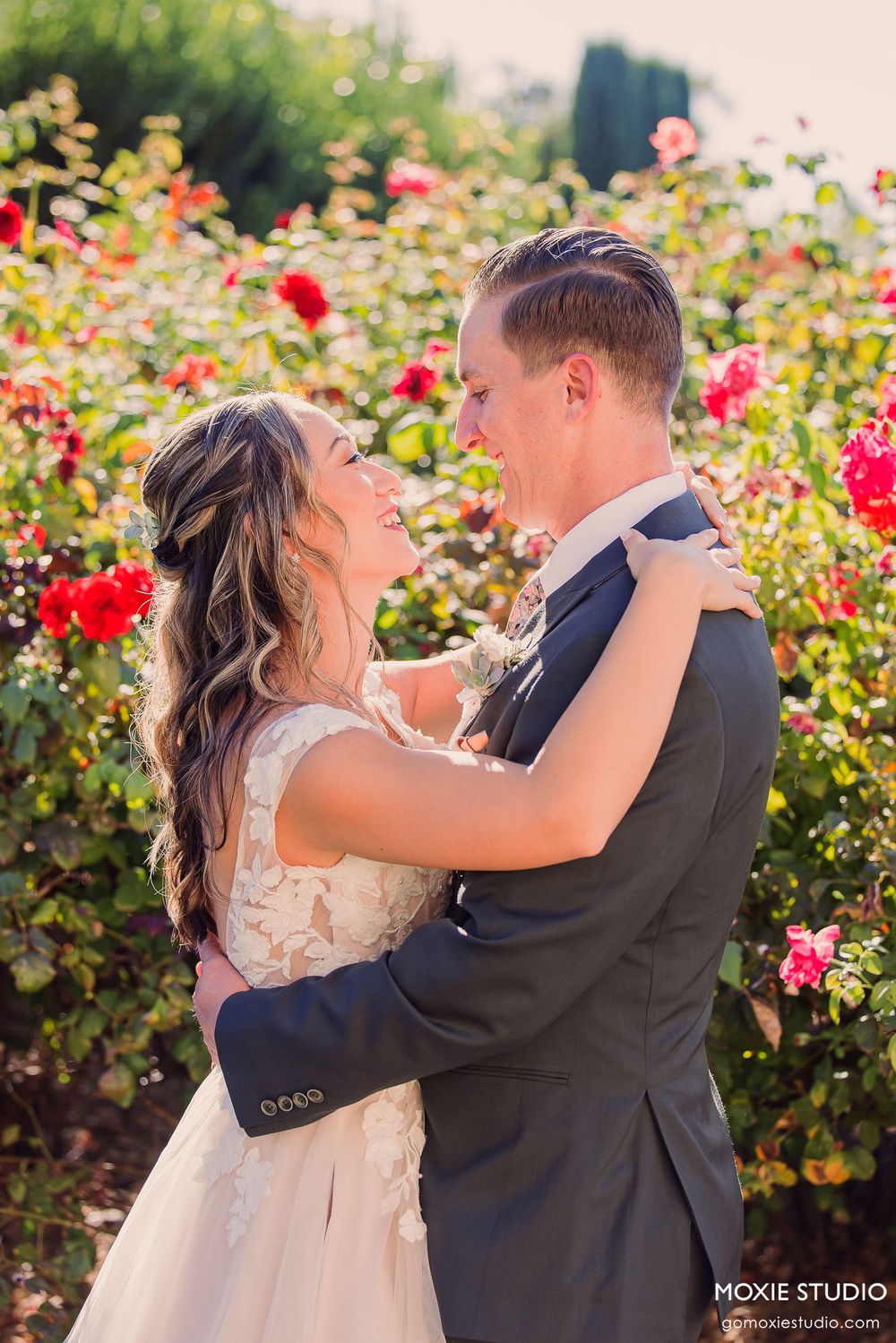 A couple shares a romantic moment dancing together in a blooming rose garden on their wedding day.