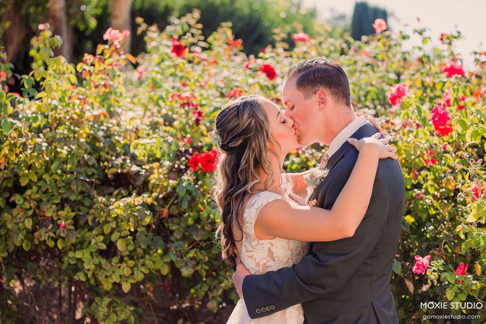 Romantic couple embraces in a blooming rose garden during golden hour.