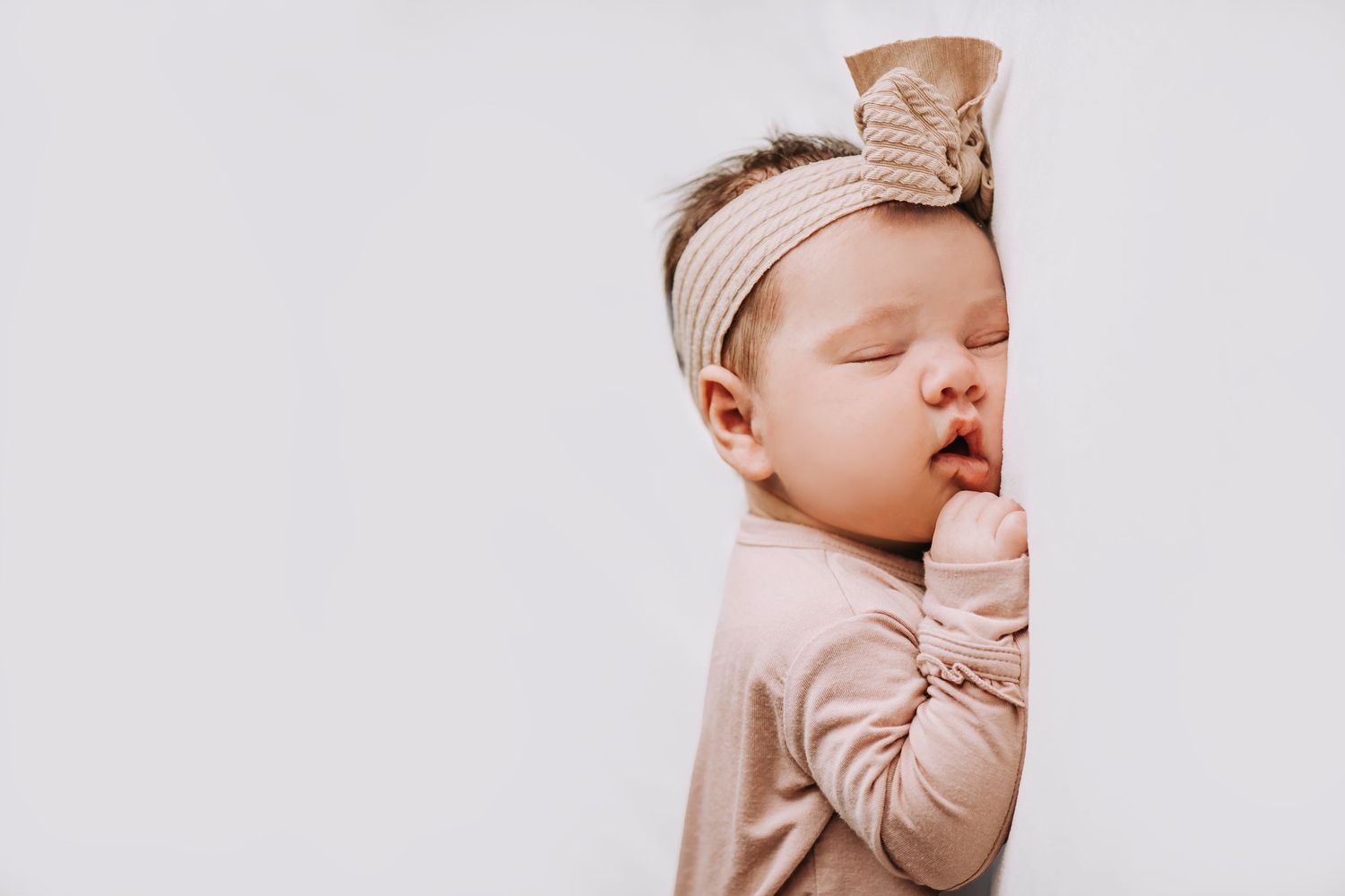 Soft beige and neutral toned baby accessories arranged on white background.