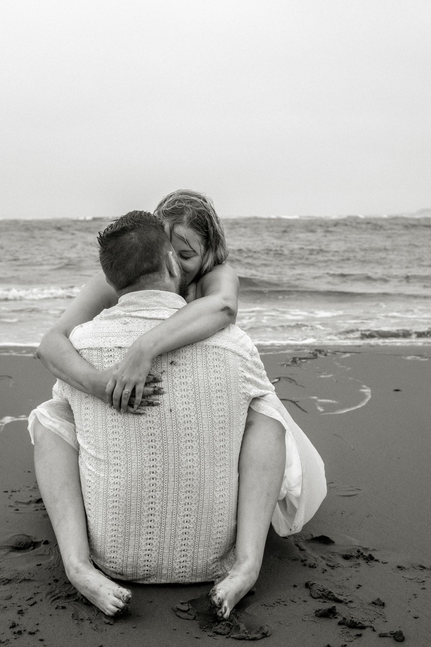 A black and white beach wedding photo capturing an intimate embrace by the ocean. Photo at Charlottetown PEI