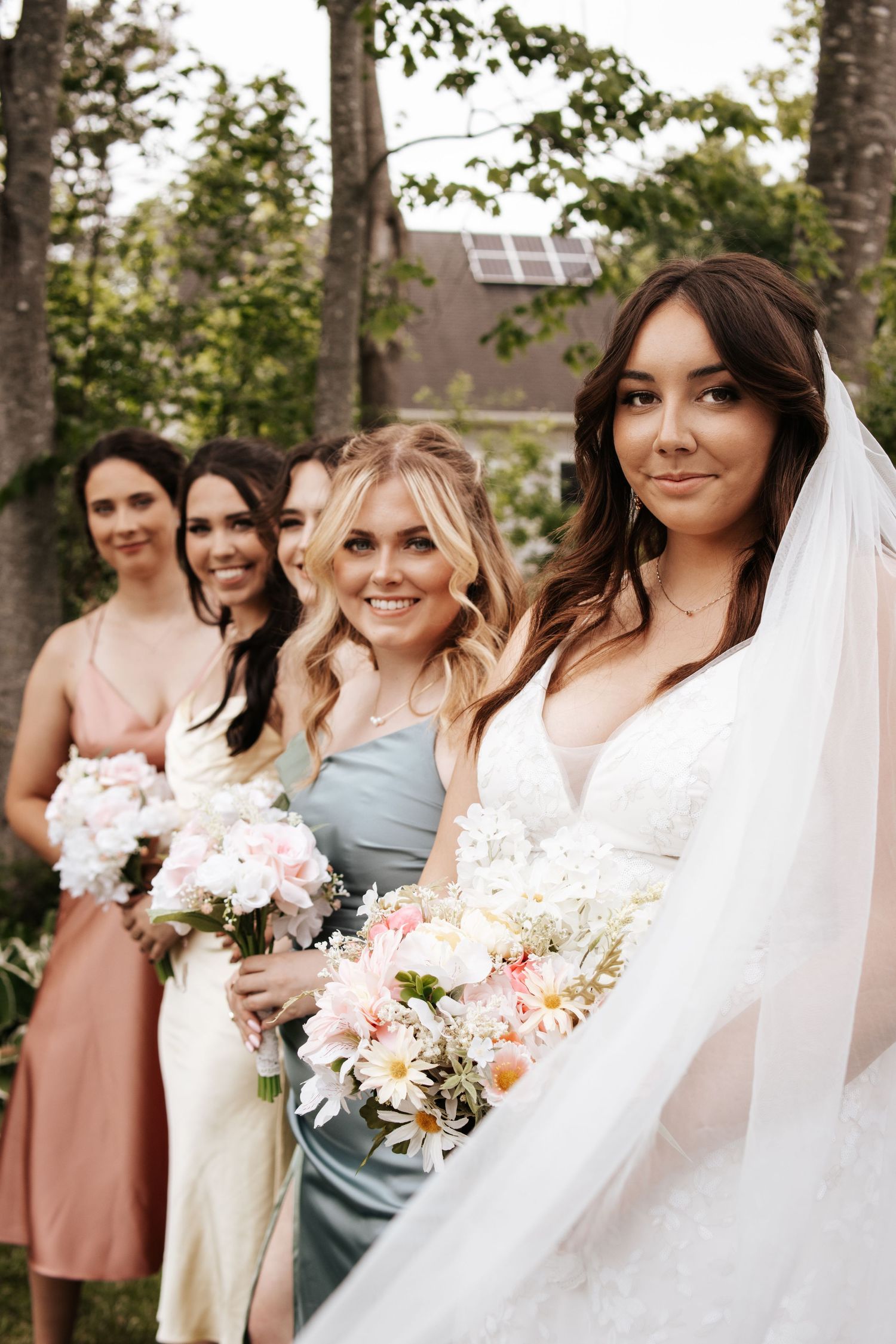 A bridal party poses together outdoors holding beautiful pink and white bouquets. Photo at Montague PEI