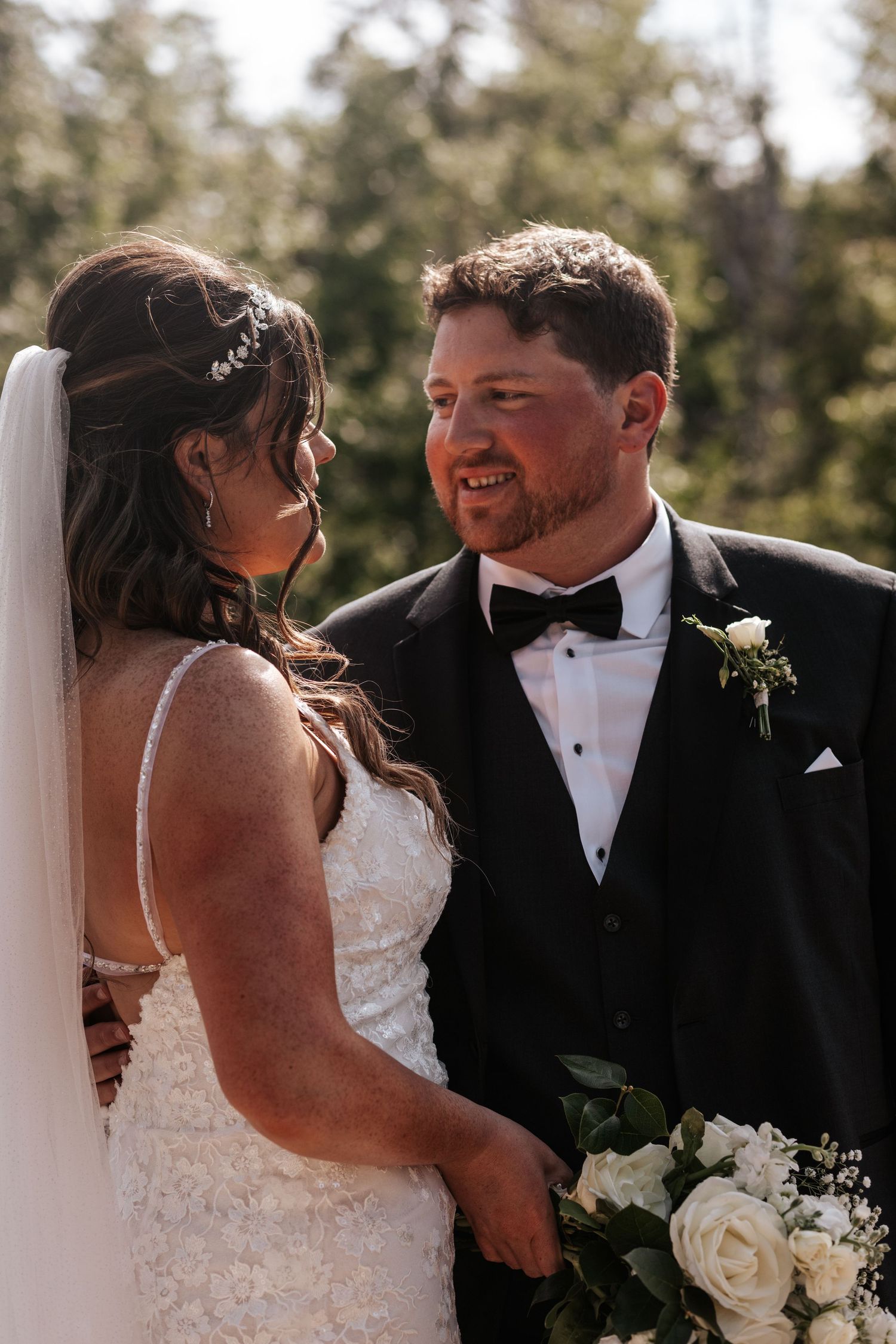 An intimate wedding photo of a couple sharing a moment in sunlit outdoor setting. Photo at Charlottetown PEI