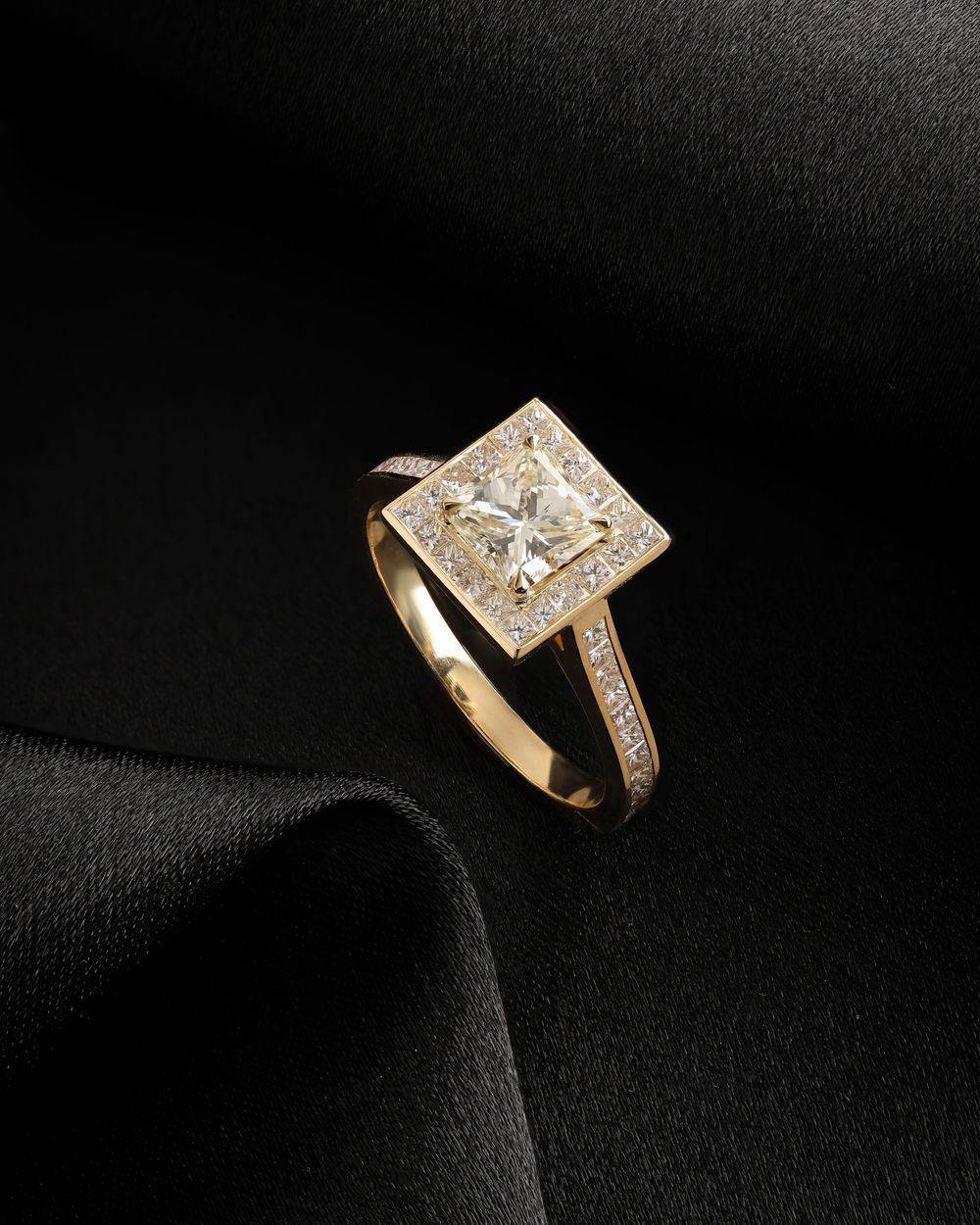 A close-up series of gold diamond engagement rings with modern geometric designs shown against a black background.