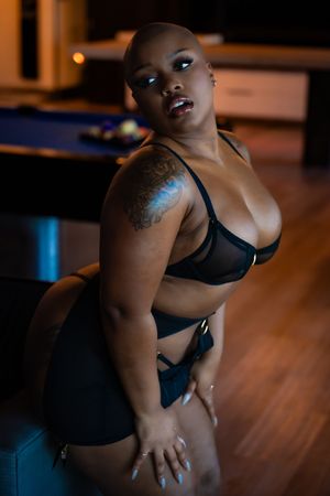 Artistic boudoir photography with warm ambient lighting and dark interior setting.