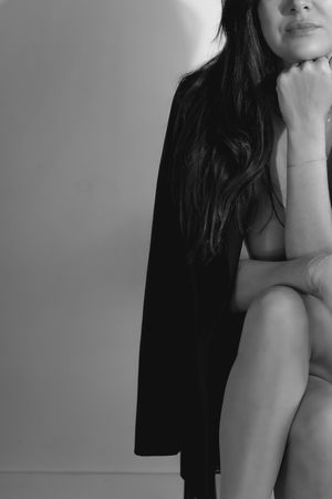 Black and white artistic portrait showing crossed legs and torso wearing a dark blazer in minimalist style.