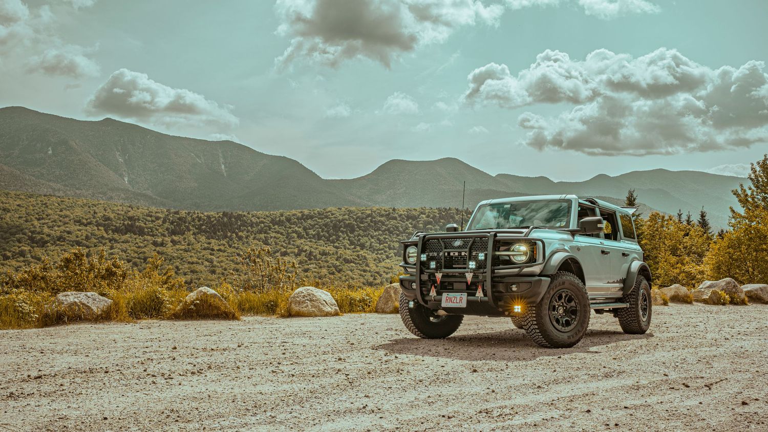 A panoramic desert landscape collage showing mountains, off-road vehicles, and dramatic cloudy skies in muted tones.