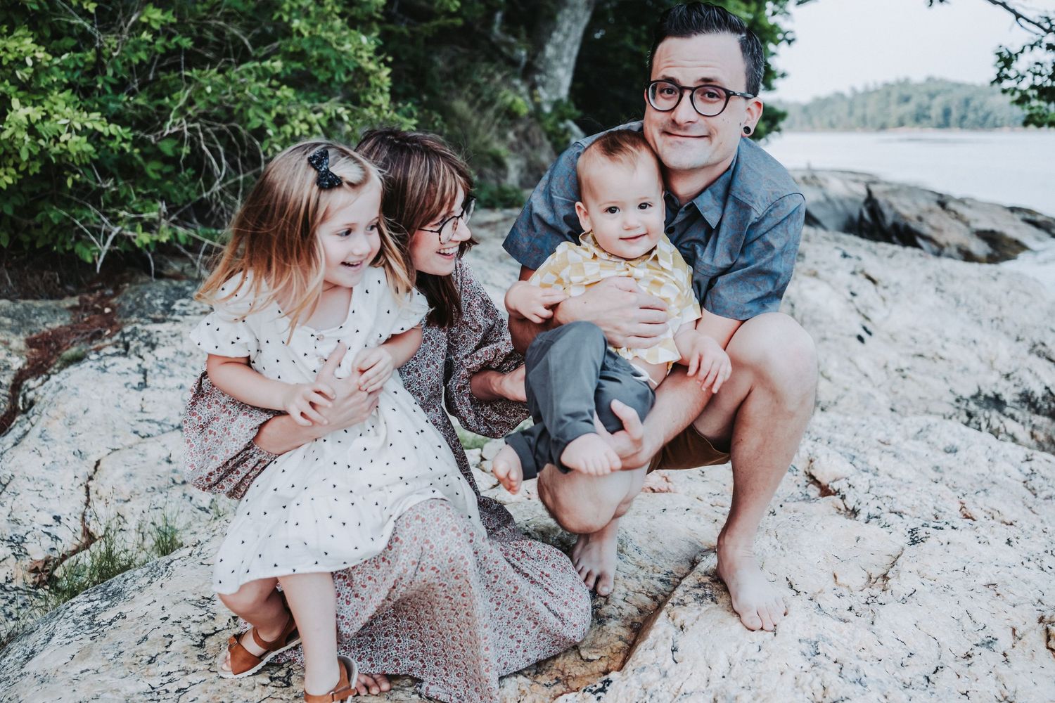 A young family poses together outdoors wearing coordinated blue and white outfits at Wolfe's Neck State Park.
