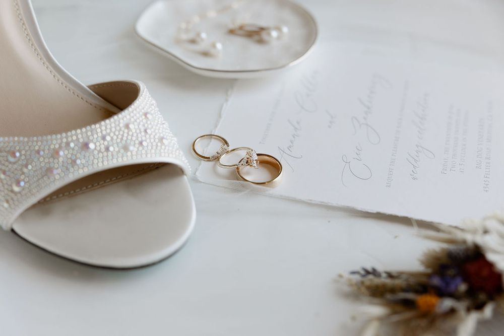 Fine art wedding details with wedding rings, delicate stationery, and white ceramic plates.