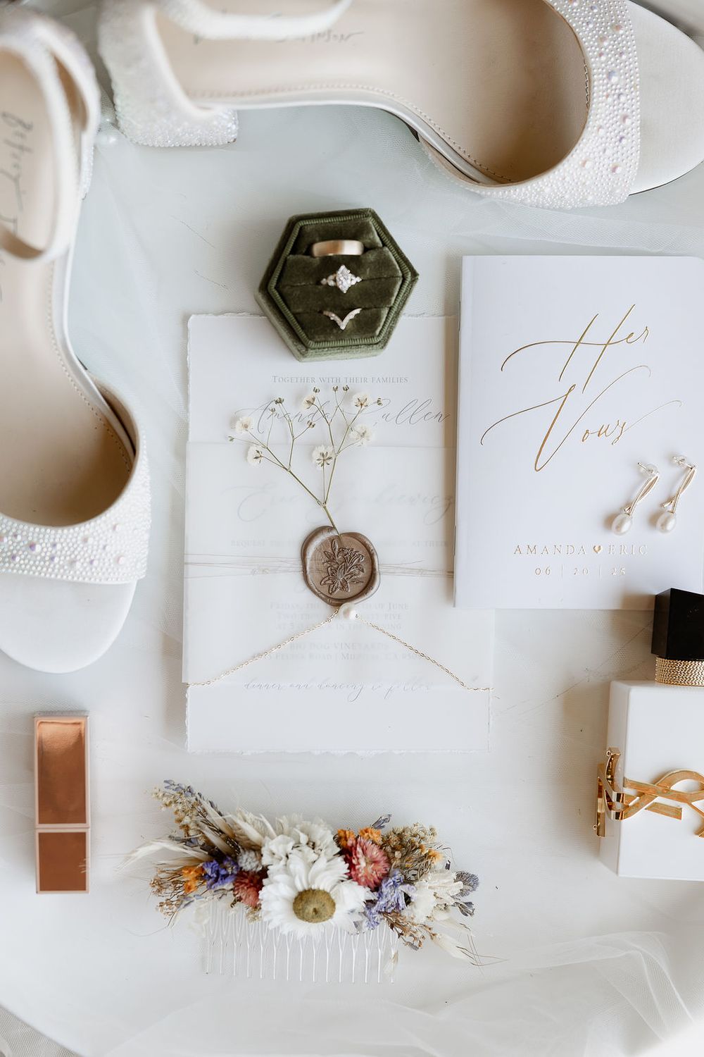 Wedding stationery and decor items arranged in white and metallic tones with delicate floral accents.