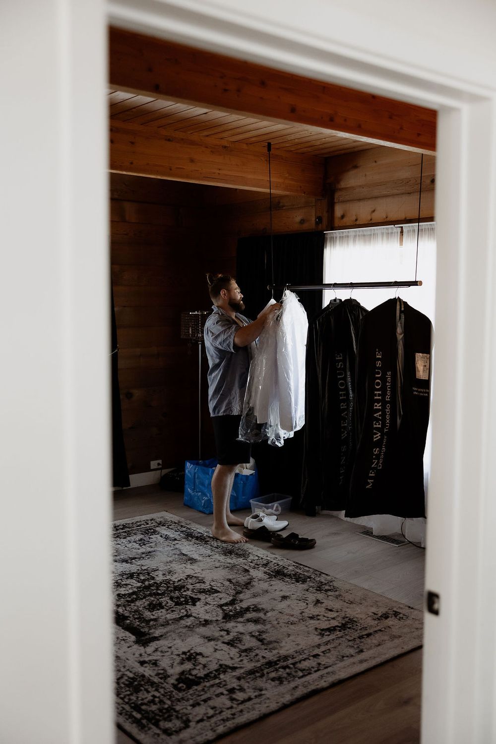Clothing hanging on racks in a dimly lit wooden interior room.