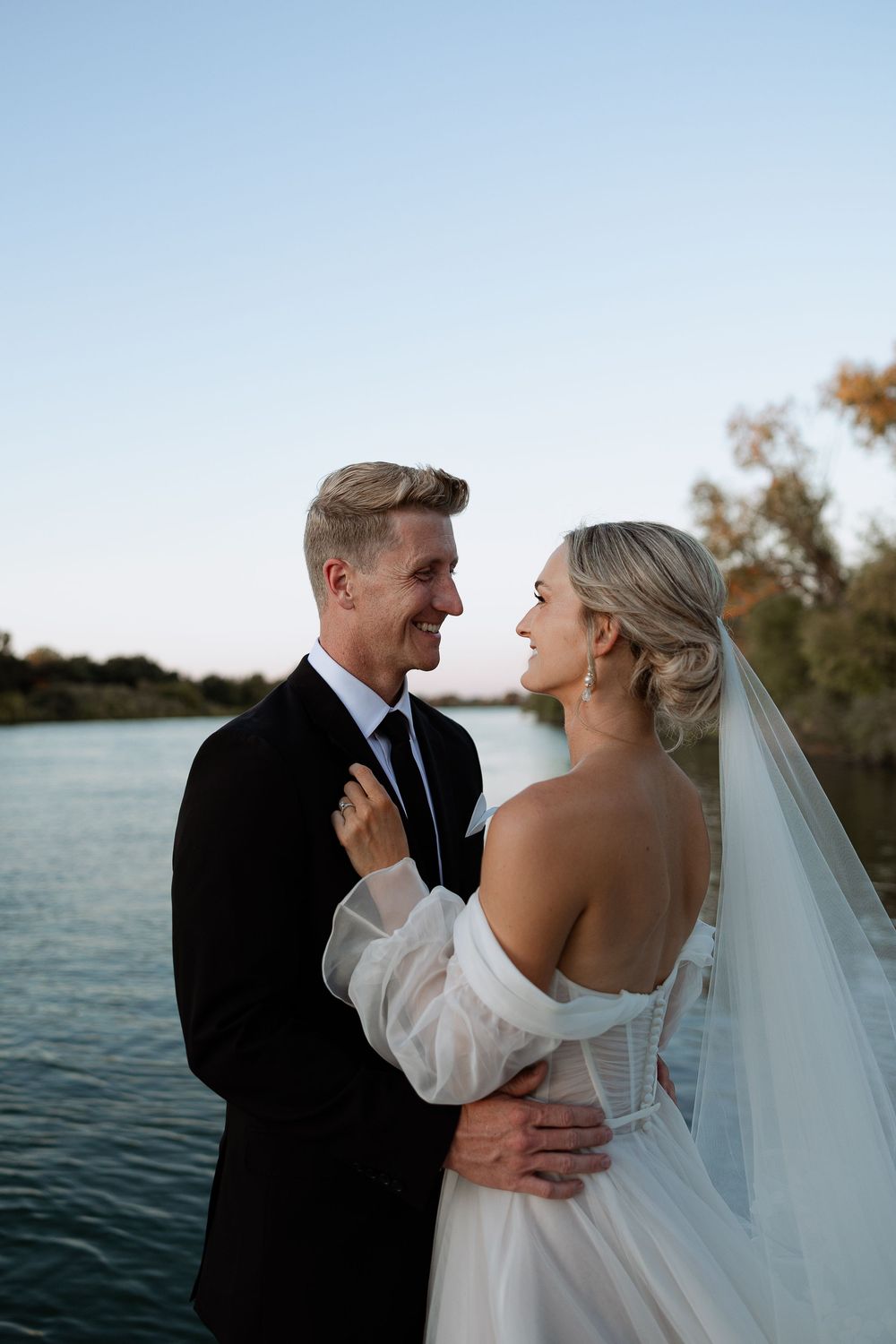 Wedding couple shares an intimate moment at sunset by the waterfront.