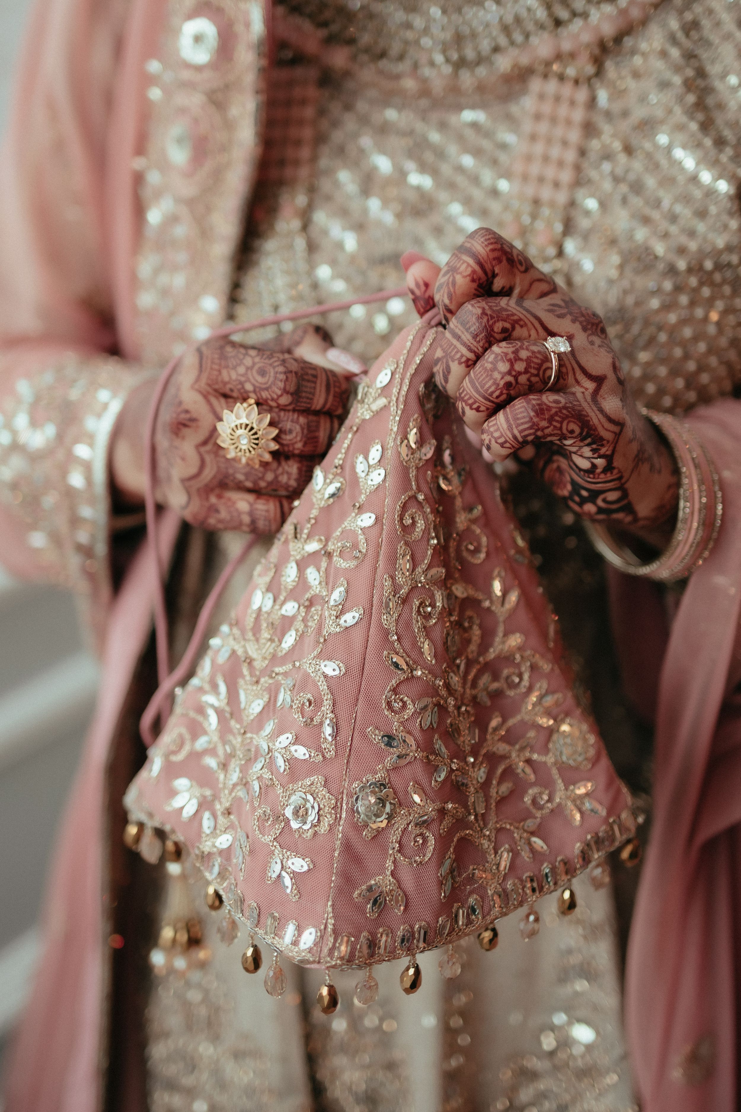 Close-up of intricate henna designs and embroidered pink fabric with gold details.