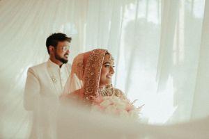 Dreamy soft-focus wedding portrait of couple in traditional South Asian attire against white backdrop.