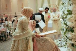 Wedding ceremony in an ornate hall with floral decorations and soft lighting.