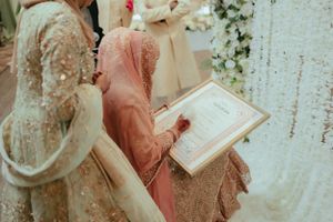 Wedding ceremony details showing traditional attire and formal documents during celebration.