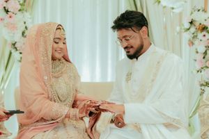 Traditional wedding ceremony with couple exchanging rings against a floral backdrop.