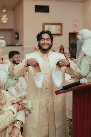 Person in cream formal attire celebrates during wedding festivities.
