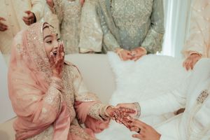 Traditional wedding ceremony moment with ornate pink dress and delicate henna details.