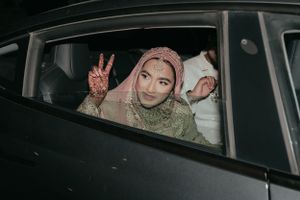 Person in car making peace sign gesture through window during nighttime celebration.