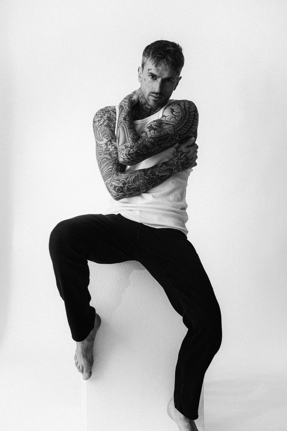 A black and white photo series shows a person in dark pants performing dynamic dance movements against a white backdrop.