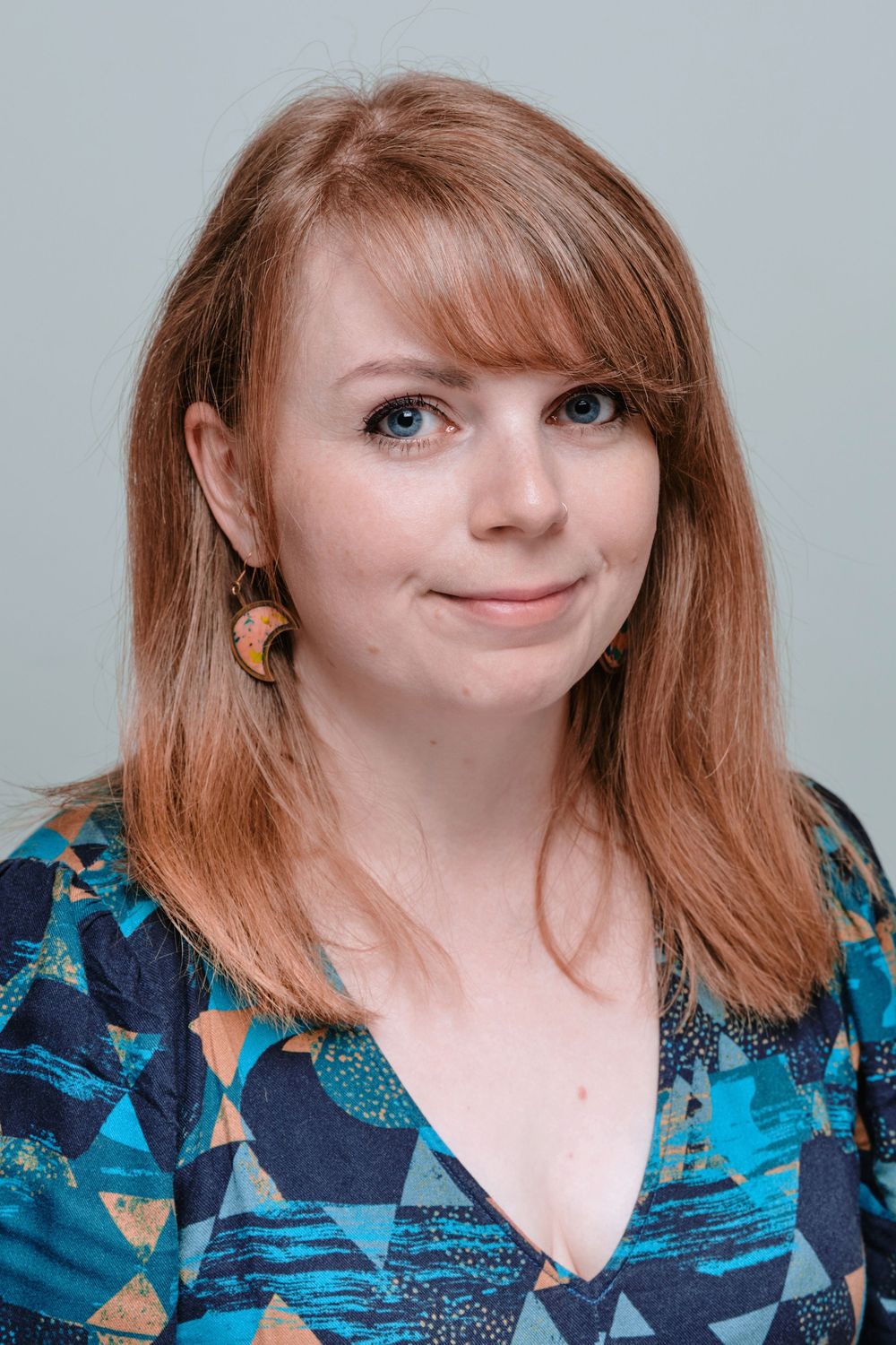 A person wearing a blue geometric patterned top smiles in a series of five similar portrait shots.