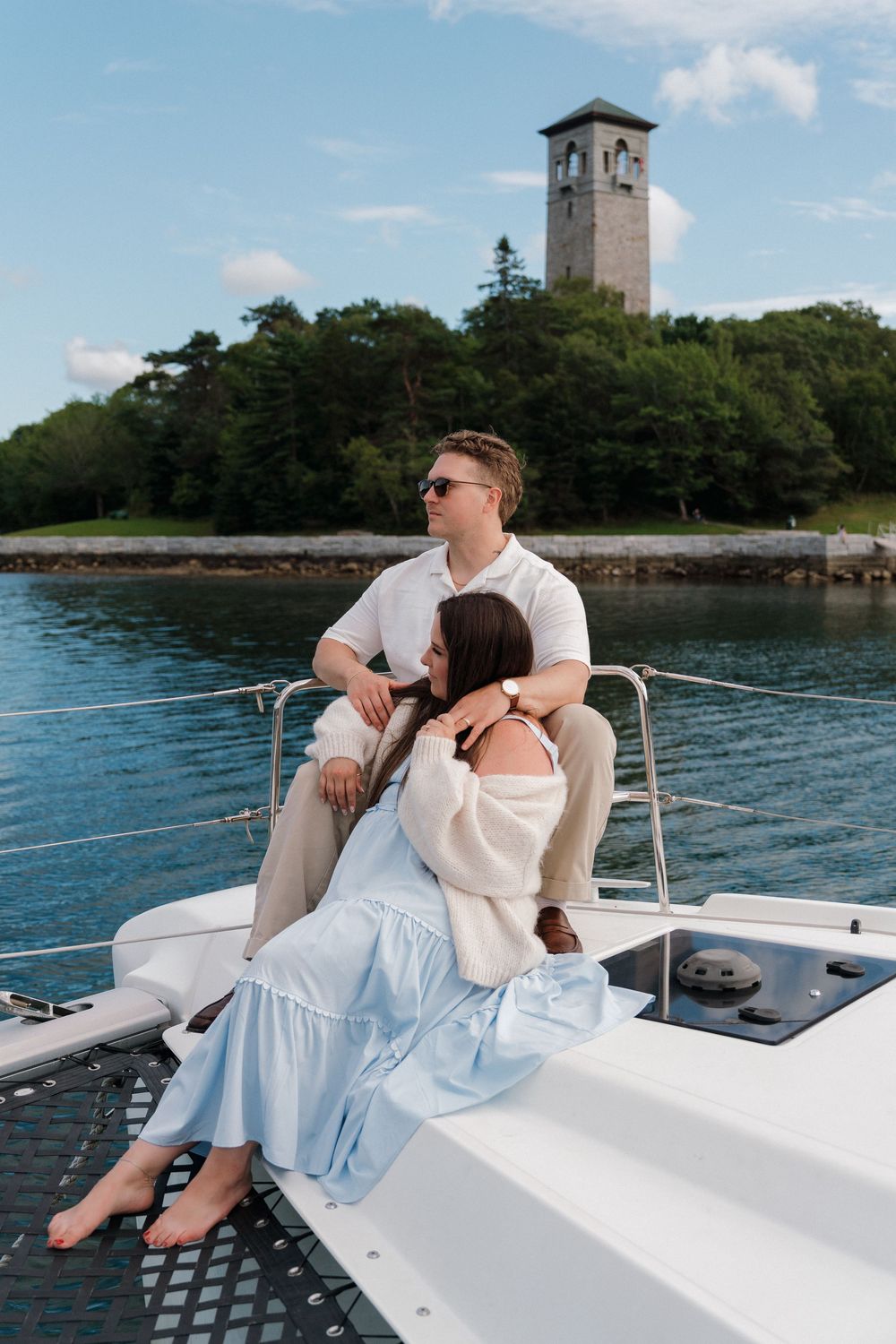 Couple relaxing on a sailboat with the Halifax Dingle tower and trees in background.
