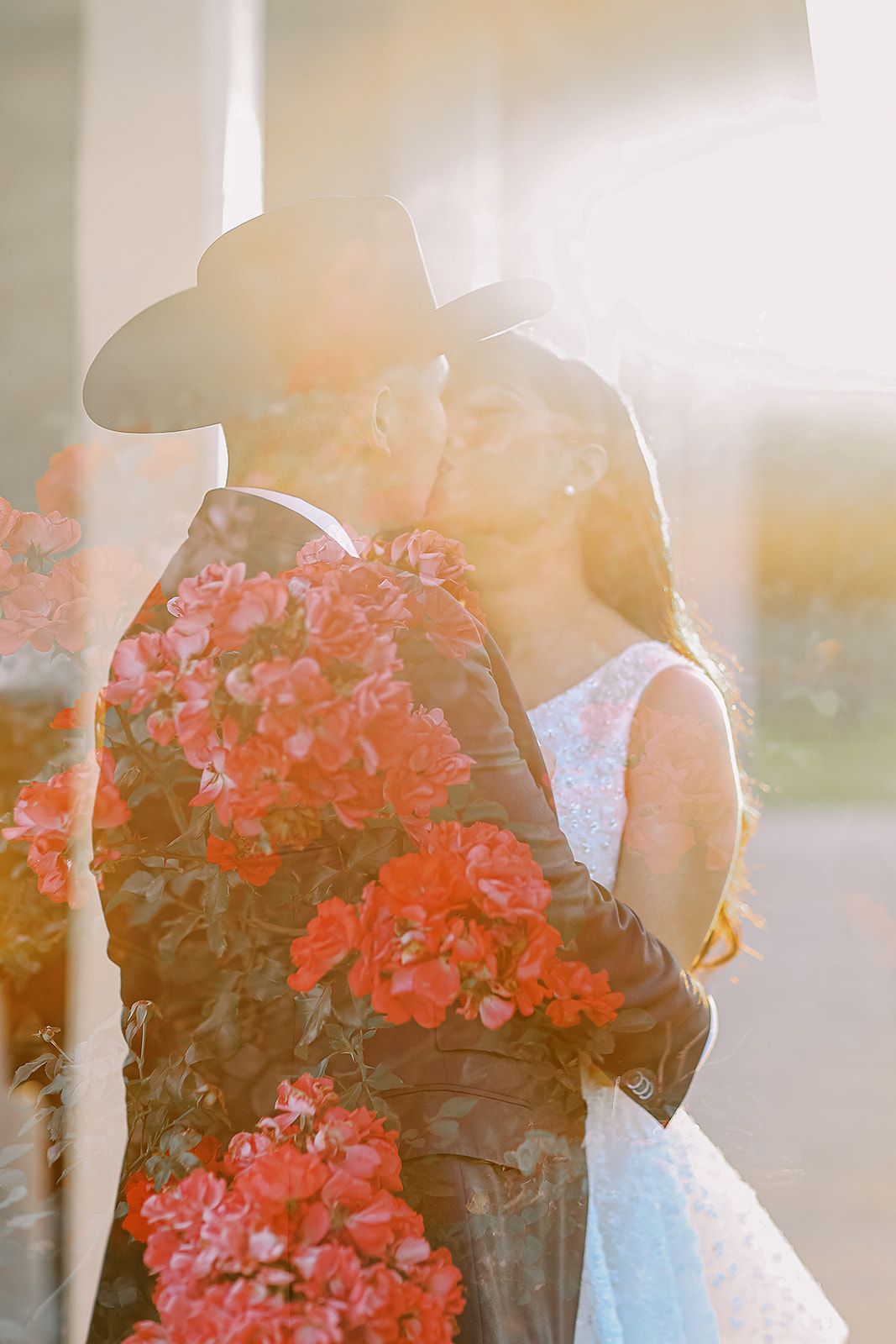 A couple walks along a stone pathway outside a white building during golden hour at their wedding celebration.
