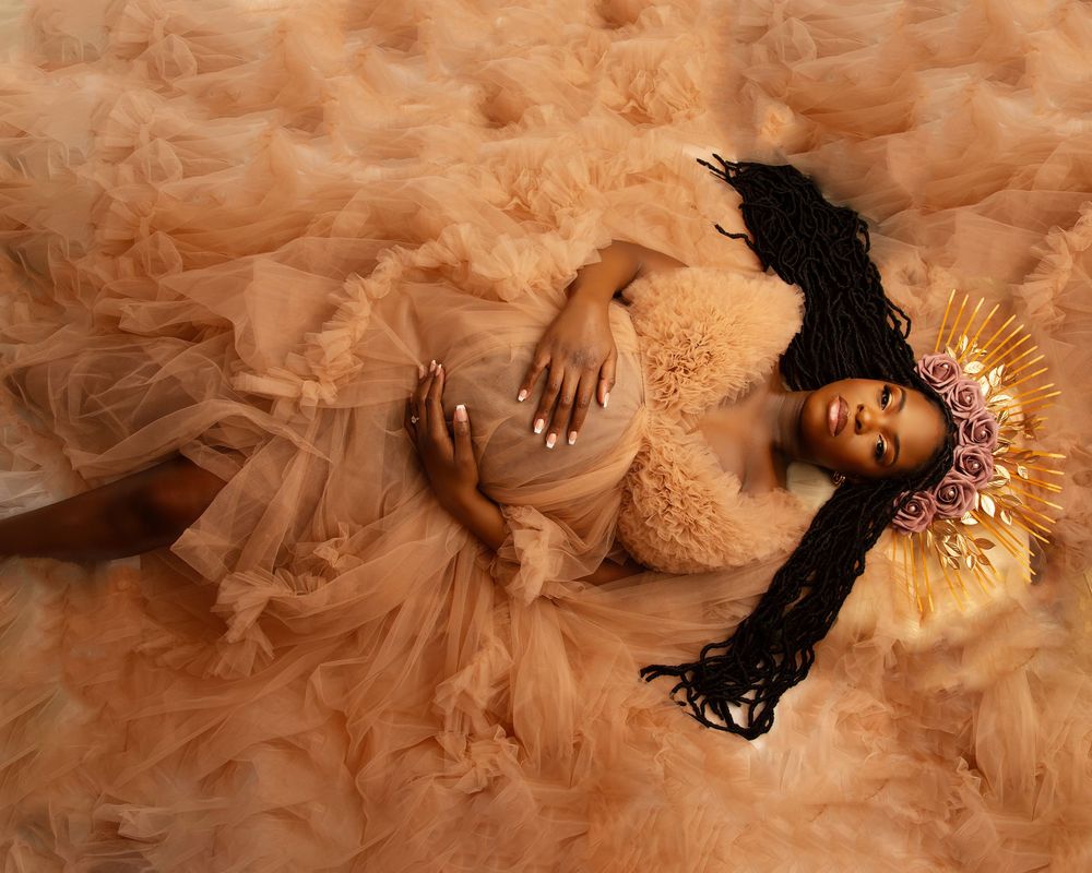 Ethereal maternity portrait with gold lighting and flowing peach dress.