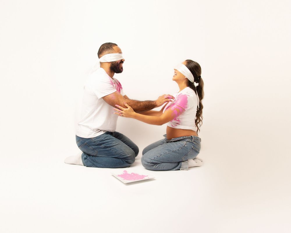 Couple in white shirts doing creative blindfolded pregnancy photoshoot.