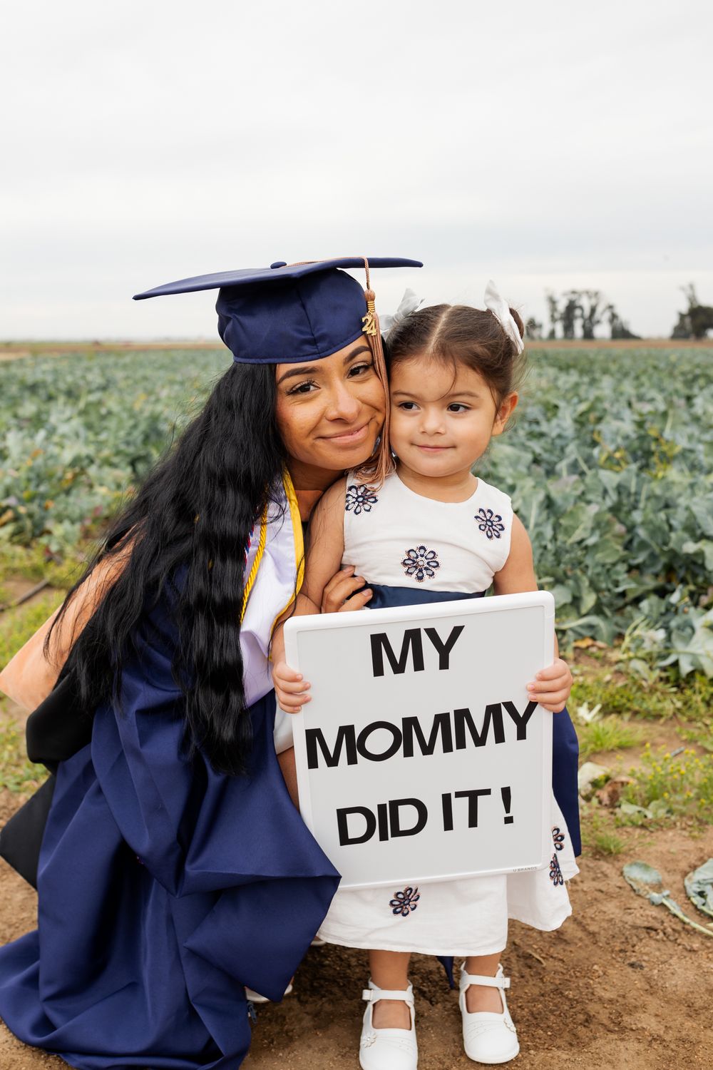 A graduation photo series showing a parent in cap and gown holding signs with their young child in a field.