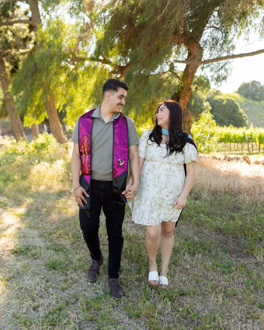 A romantic outdoor scene with two people walking together through a sunlit field with willow trees.