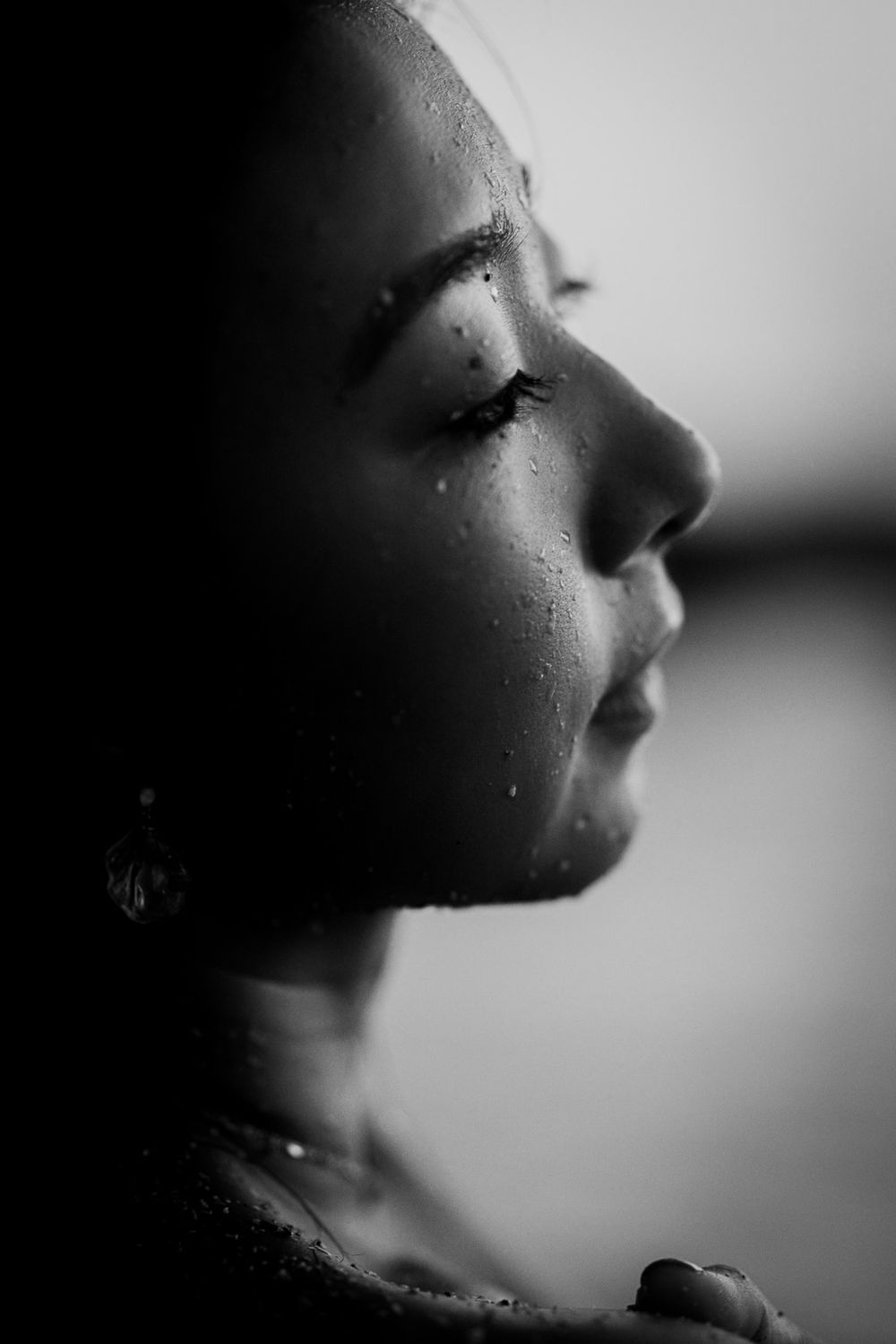 Dramatic black and white close-up profile showing water droplets on skin.