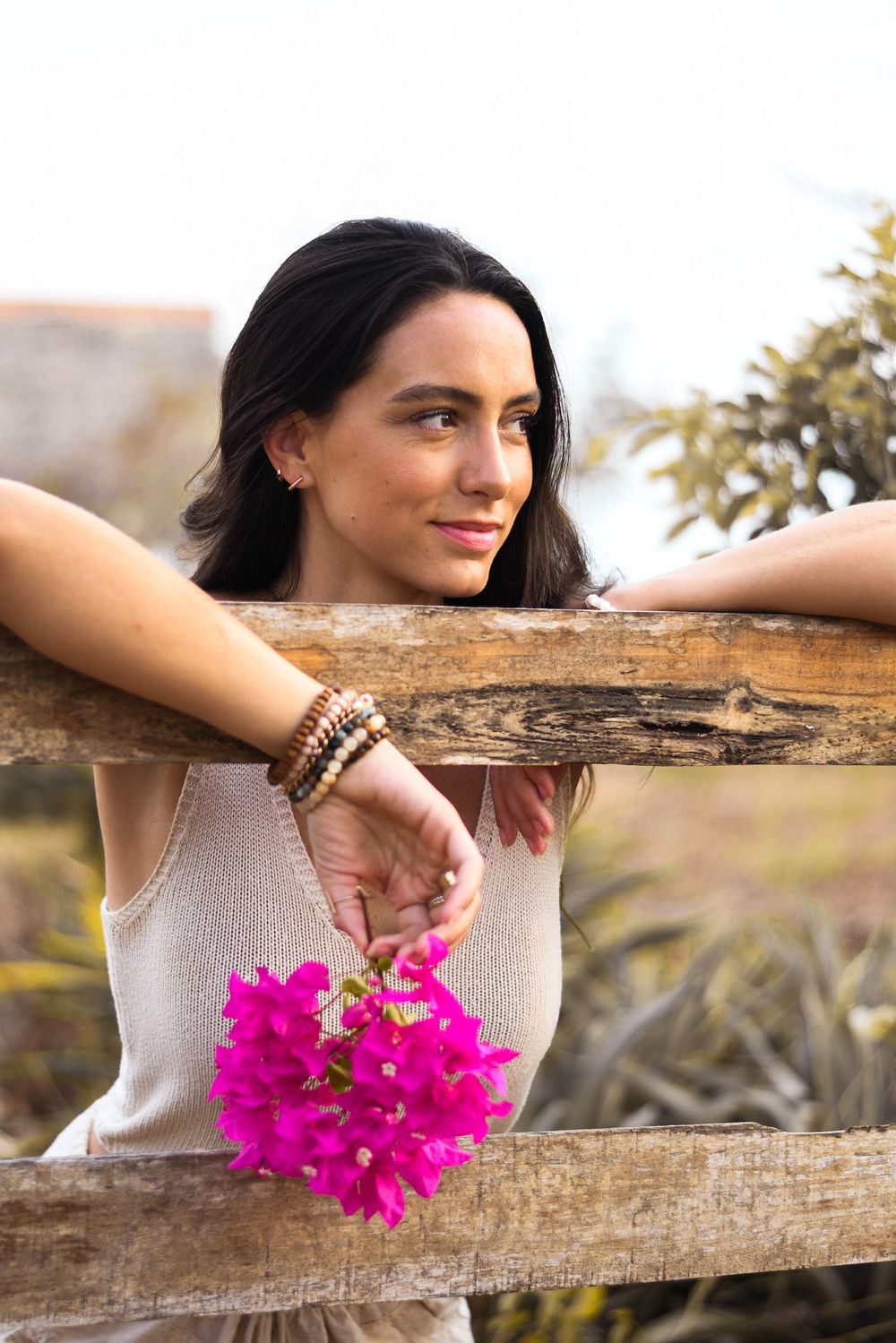 Women holding flowers leaning over a fence during a lifestyle portrait photoshoot in Playa Negra Costa Rica