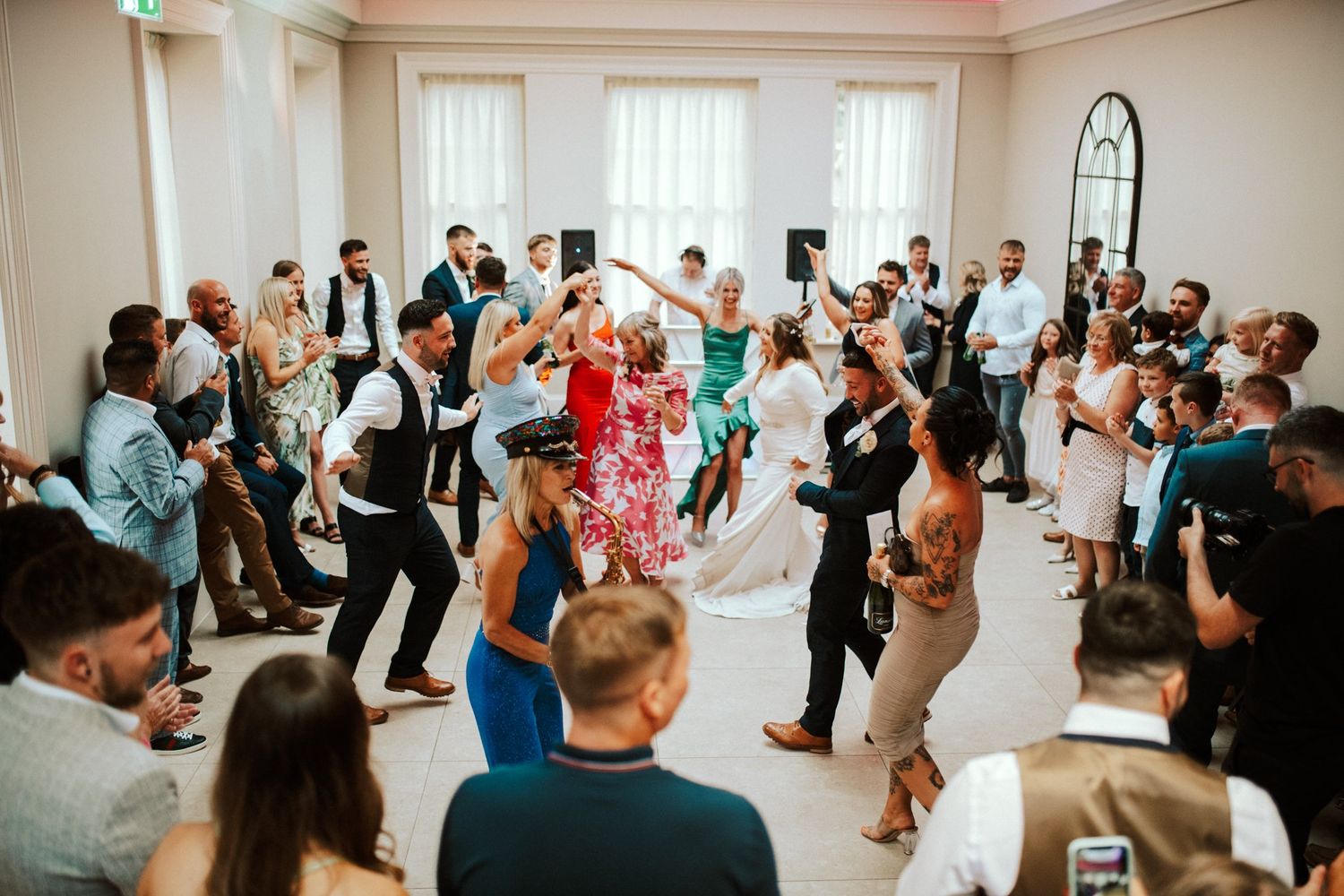 Wedding reception guests dancing and celebrating on a lively dance floor.